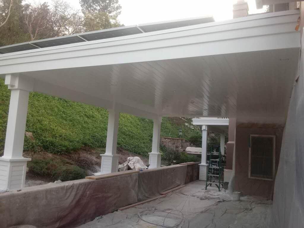 Full view of nearly completed white patio cover with solar panels and painted columns — Orange County CA