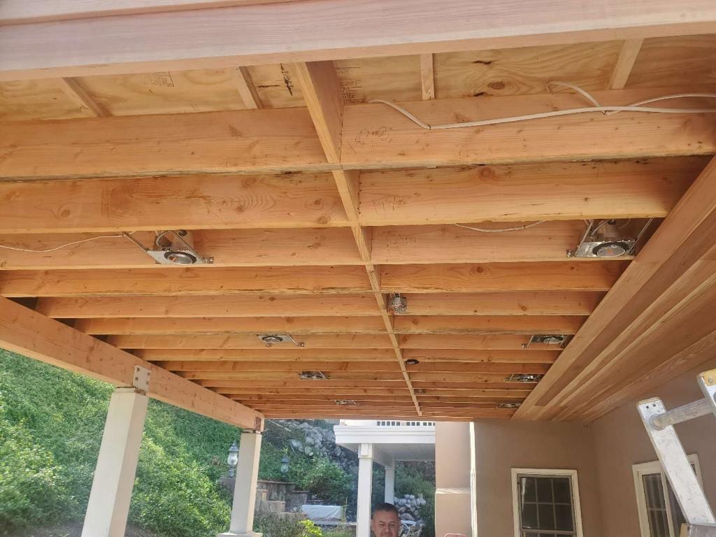 Completed patio cover with finished wood ceiling beams and recessed lighting — Orange County CA